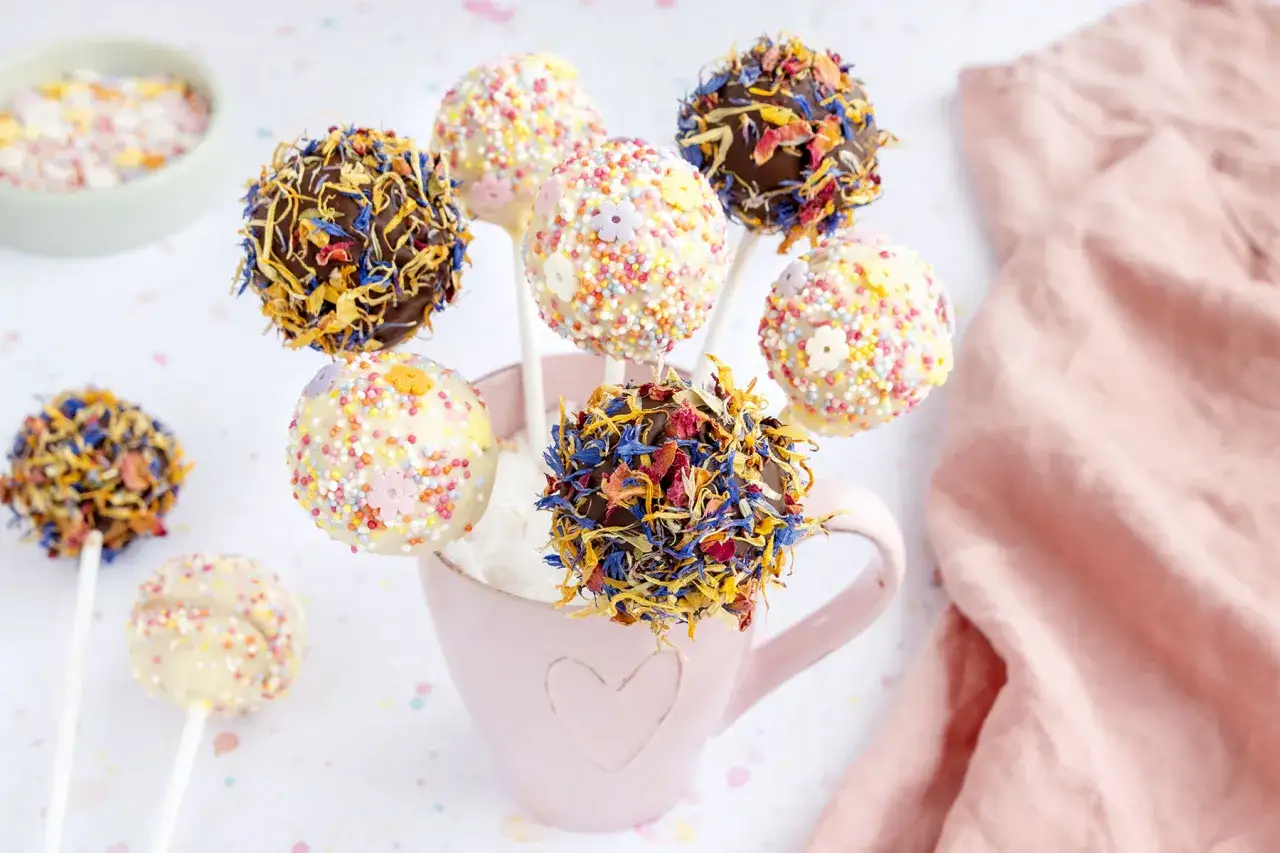 Bunte Cake Pops mit Streuseln und Blüten, ein tolles Rezept für jede Feier.