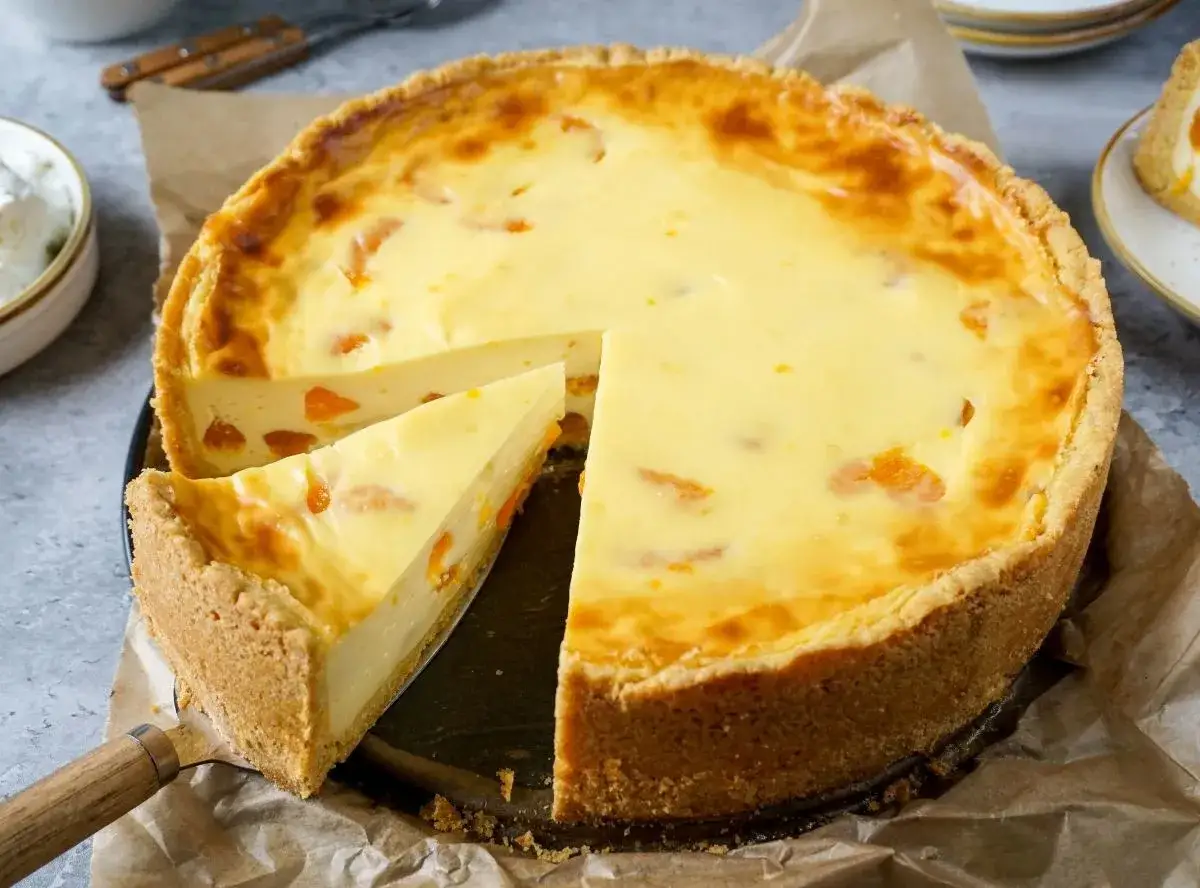 Ein saftiger Mandarinen Schmand Kuchen Blech, mit einem Stück herausgeschnitten, zeigt die cremige Füllung und den knusprigen Boden.