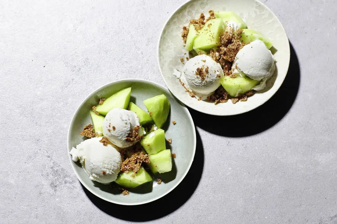 Zwei Schalen mit erfrischendem Eis aus Quark, garniert mit saftigen Melonenst&uuml;cken und knusprigen Streuseln.