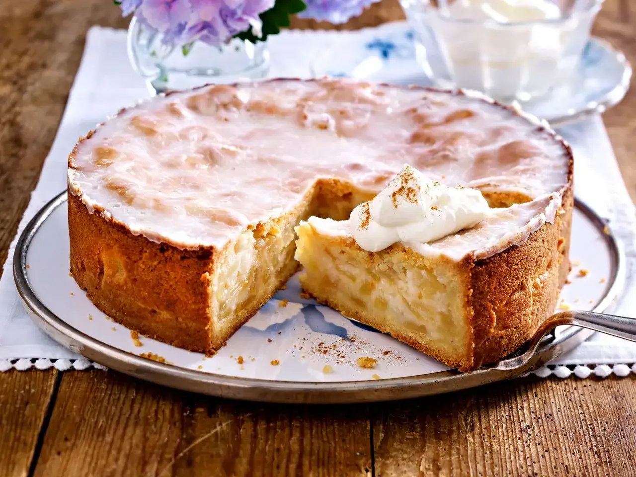 Ein saftiger gedeckter Apfelkuchen mit einer süßen Glasur und einem Klecks Sahne, der an Apfelmus erinnert.