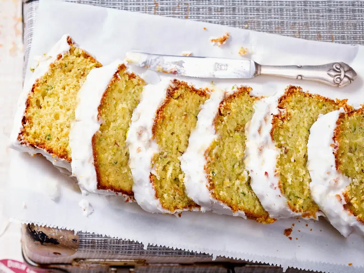 Saftiger Zucchini Kuchen mit weißer Glasur, in Scheiben geschnitten, bereit zum Genießen.
