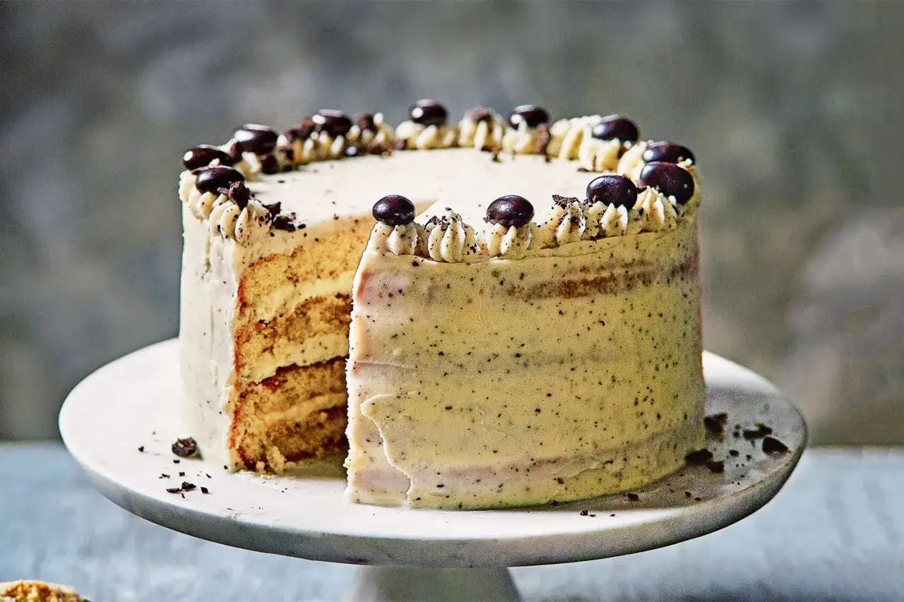 Eine köstliche tiramisu torte mit Kaffeebohnen und Schokoladenstückchen verziert, auf einem weißen Tortenständer.