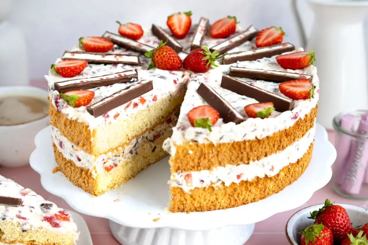 Saftige Joghurette Torte mit Erdbeeren und Schokostückchen, dekoriert mit frischen Erdbeeren und Schokoriegeln.