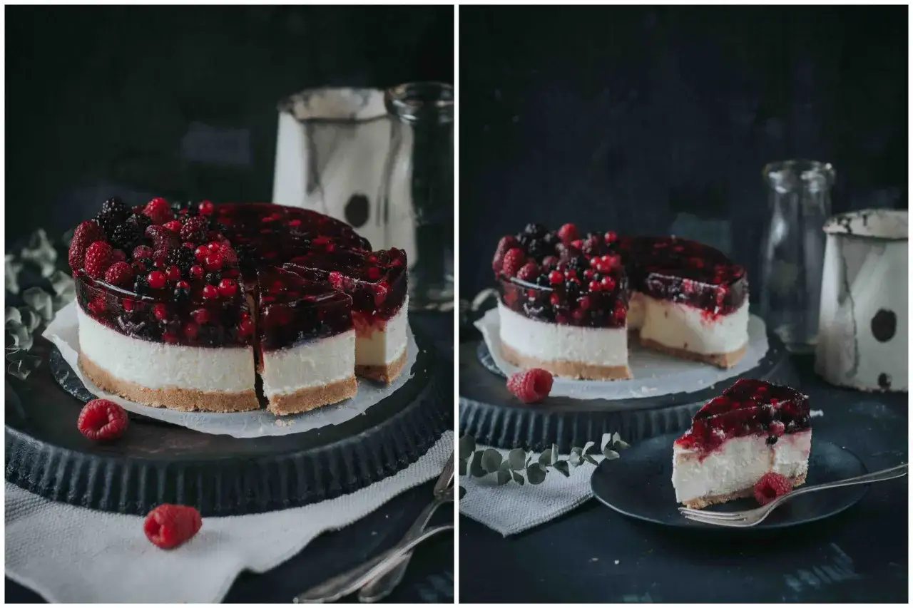 Eine köstliche Philadelphia Torte mit frischen Beeren und Gelee-Schicht, auf einem dunklen Teller mit einer Gabel.