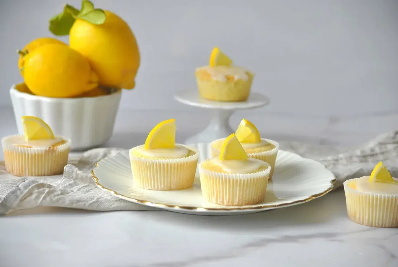 Erfrischende Zitronenmuffins mit Zuckerguss und Zitronenspalten. Ein tolles Rezept für Zitronenmuffins!