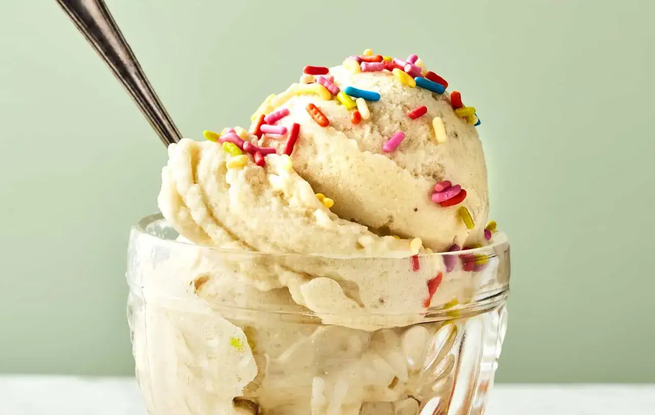 Ein Löffel steckt in einer Schüssel mit cremigem italienischem Bananeneis, bestreut mit bunten Streuseln.