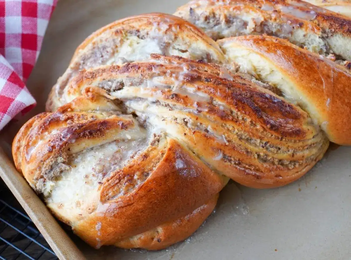 Goldbrauner Nusszopf, frisch gebacken und mit Zuckerguss verziert. Ein köstliches Rezept für jeden Anlass.