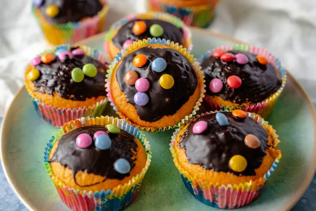 Bunte schokomuffins kinder, verziert mit Schokoladenglasur und bunten Smarties. Ein süßer Genuss für kleine Naschkatzen.