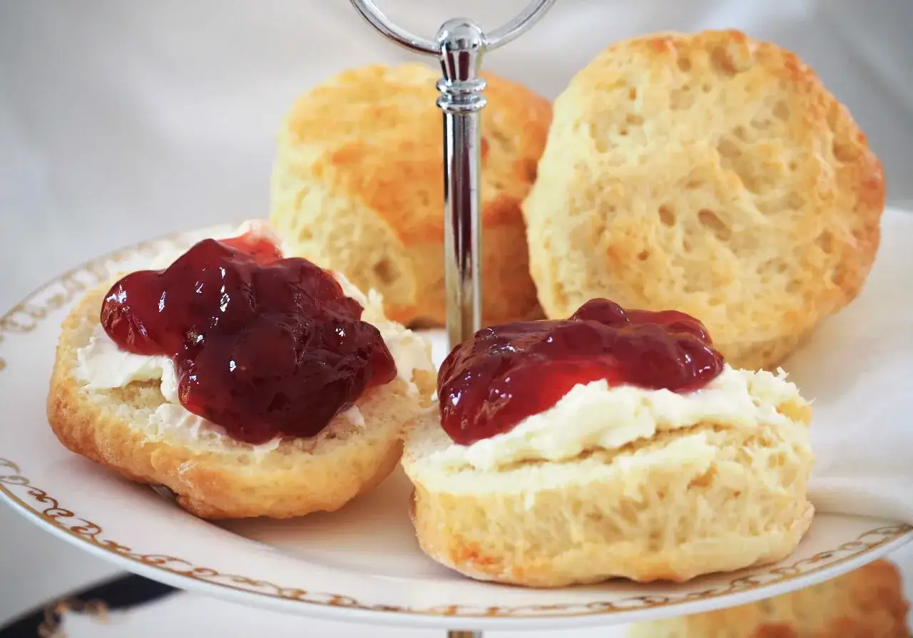 Zwei Scones mit Clotted Cream und Marmelade auf einer Etagere. Ein köstliches Scones Rezept zum Nachbacken.