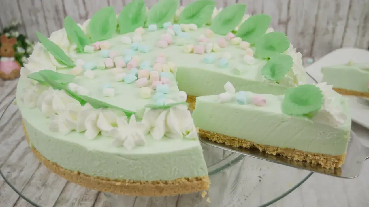 Eine helle, cremige Philadelphia Torte Waldmeister, verziert mit bunten Marshmallows und grünen Blättern.