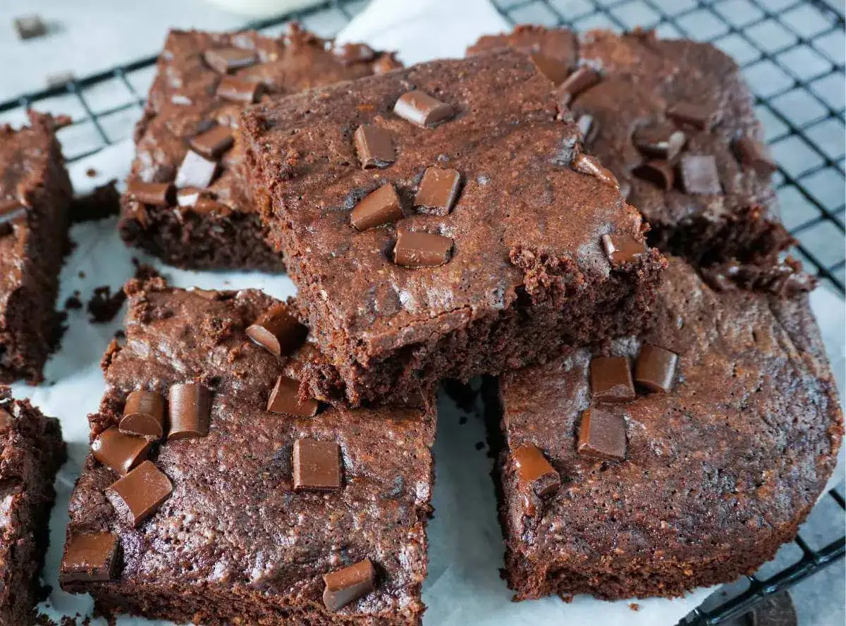 Saftige Zucchini Brownies mit Schokostückchen, auf einem Gitterrost arrangiert. Ein Genuss für Schokoladenliebhaber!