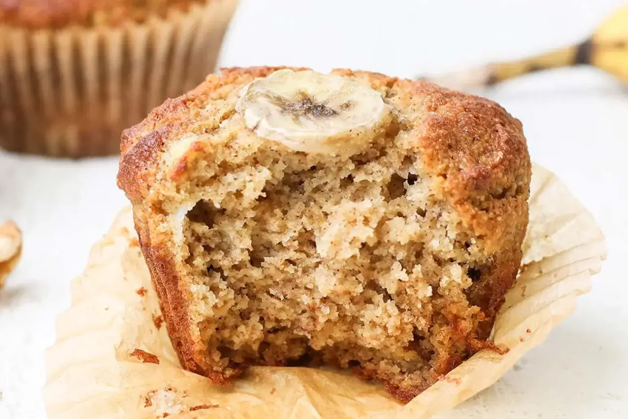 Ein aufgeschnittener Muffin mit Bananenscheibe obendrauf, der die saftige Textur von bananenmuffins ohne zucker zeigt.