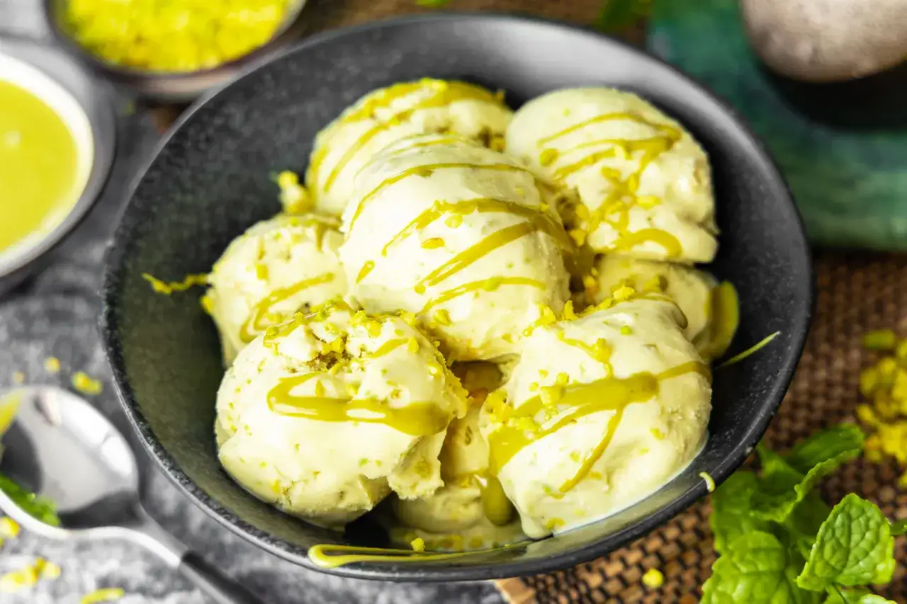 Schüssel mit cremigem Pistazieneis, beträufelt mit Pistaziencreme und bestreut mit gehackten Pistazien.