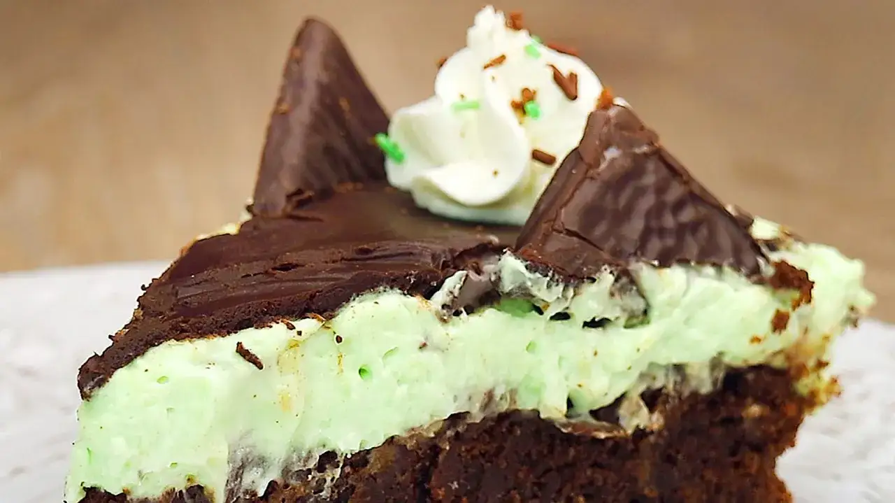 Ein Stück After Eight Torte mit Schokoladenboden, Minzcreme, Schokoladenglasur und Sahnetupfer.