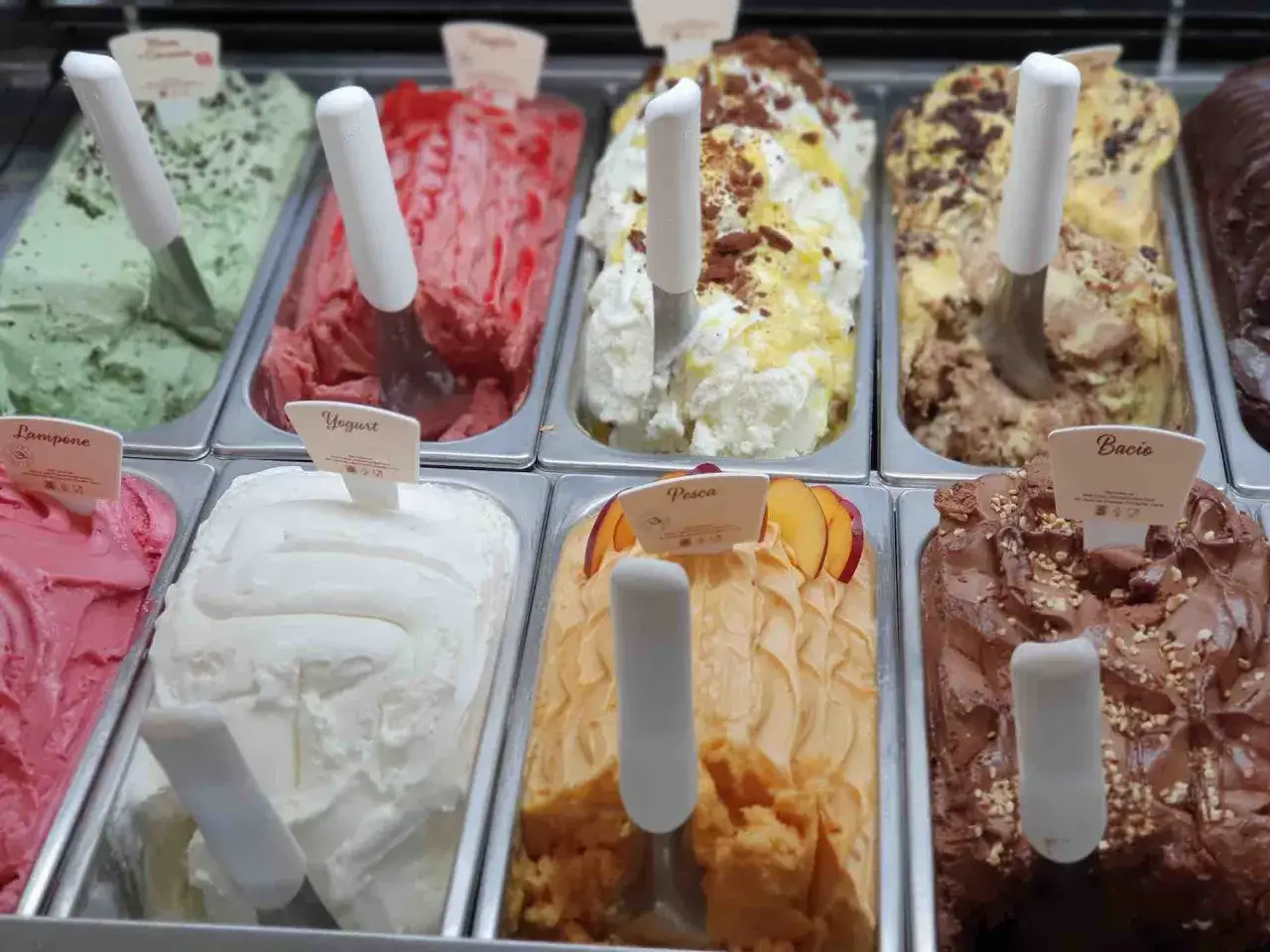 Vielfalt an eis sorten: cremiges Vanilleeis mit Schokostückchen, fruchtiges Pfirsicheis, grünes Minzeis und mehr.