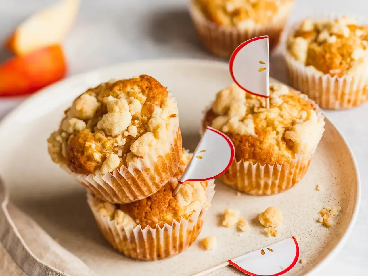 Saftige Apfel Streusel Muffins mit süßen Apfel-Deko auf einem Teller.