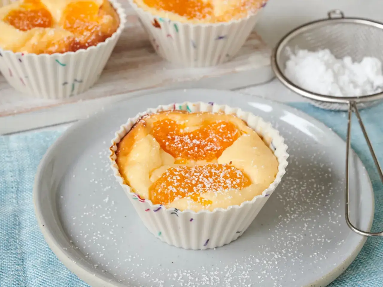 Saftige cheesecake muffins mit Mandarinenstücken, bestäubt mit Puderzucker.