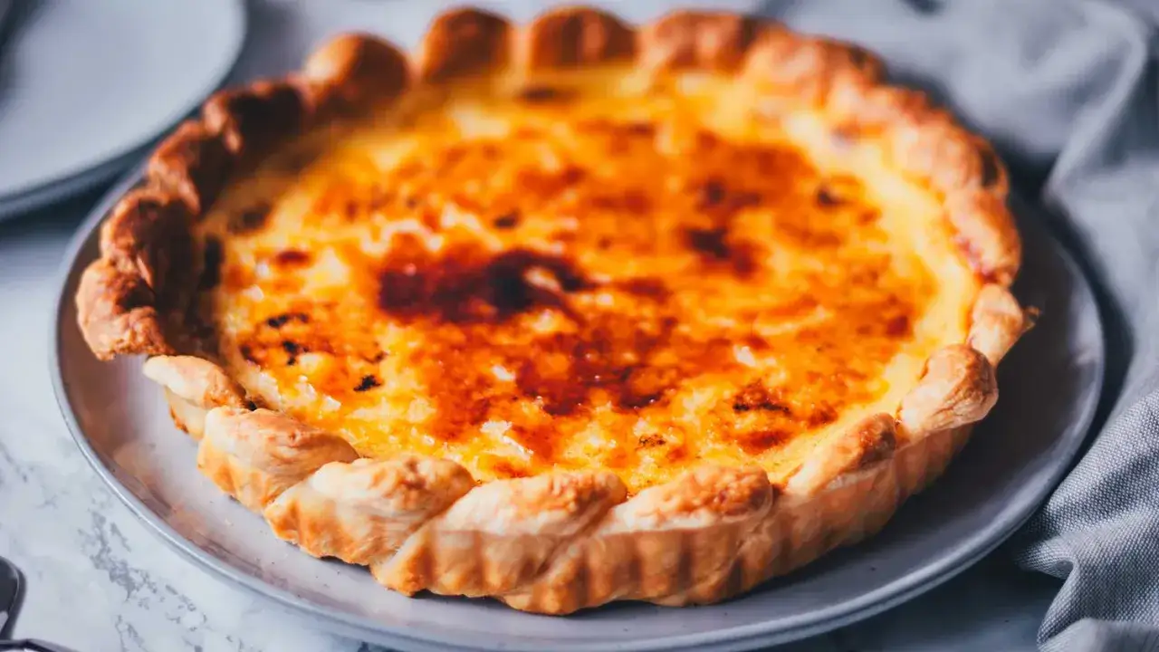 Ein goldbrauner, karamellisierter Kuchen, der an Pastéis de Nata erinnert, mit knusprigem Blätterteigrand.