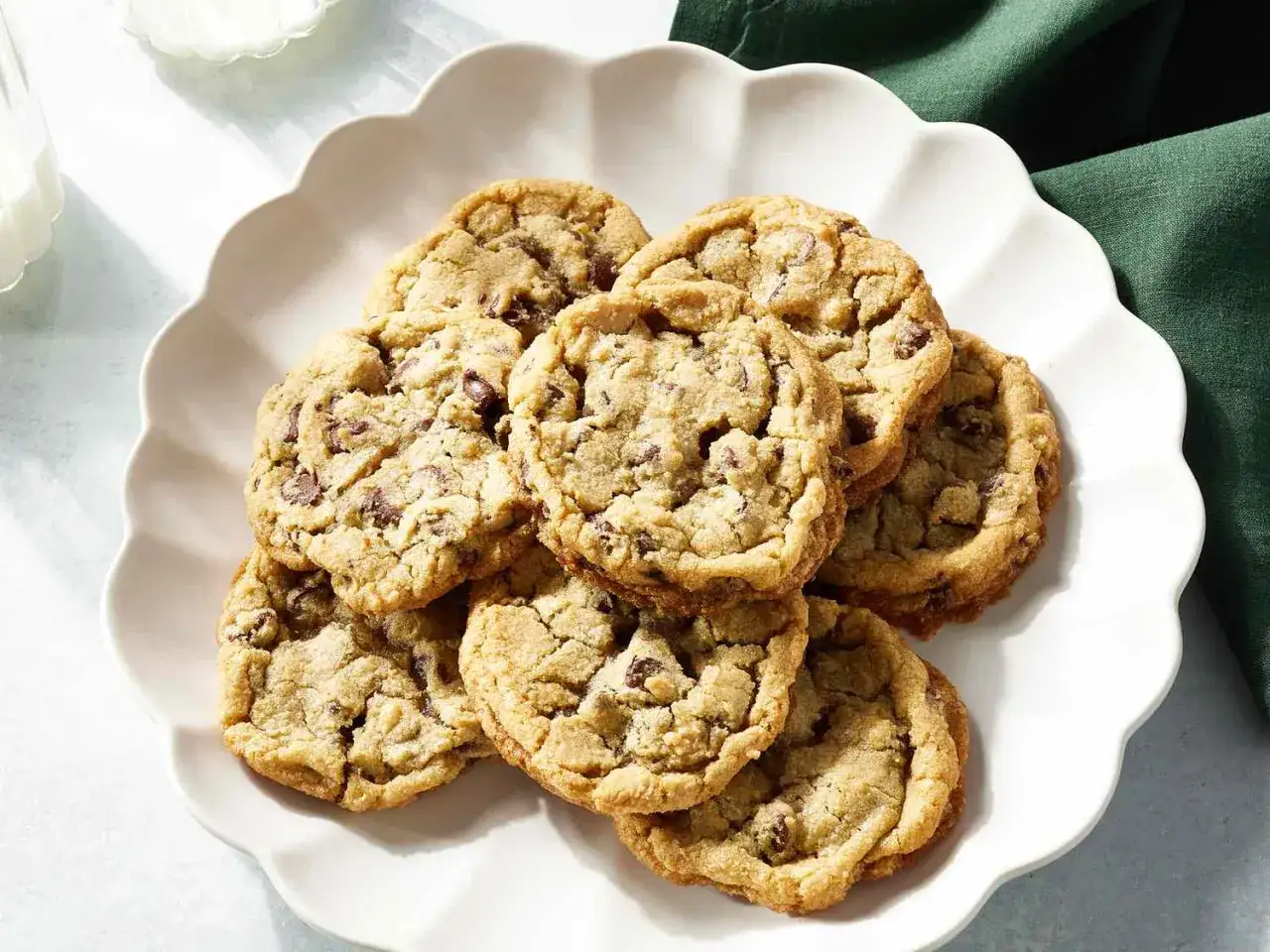 Ein Haufen saftiger american cookies mit Schokoladenstückchen auf einem weißen Teller, bereit zum Genuss.