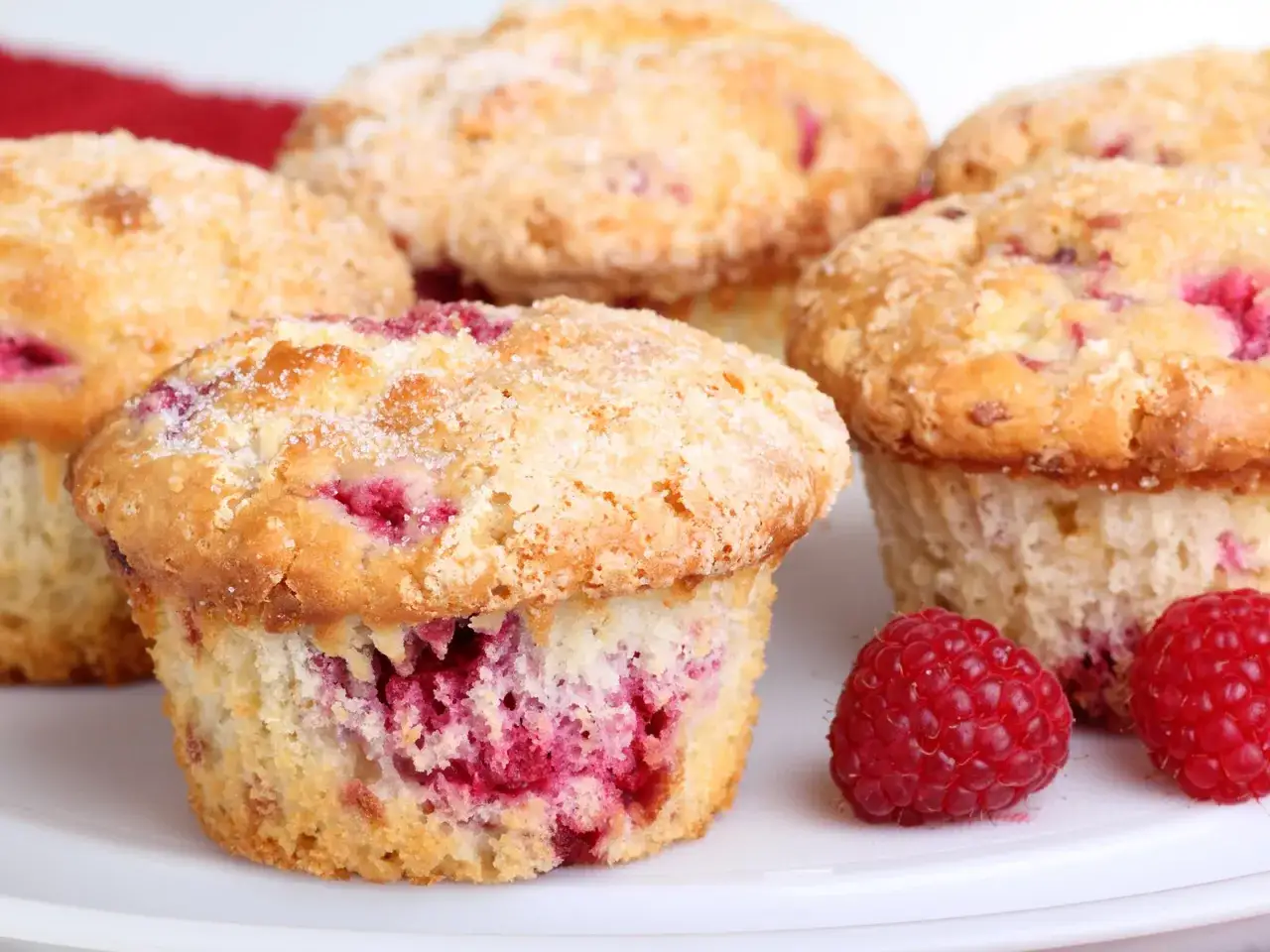 Frisch gebackene Himbeer Muffins, bestreut mit Zucker, verlocken zum Genuss.