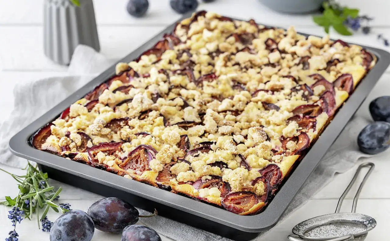 Ein frisch gebackener Zwetschgenkuchen vom Blech, bedeckt mit Streuseln und saftigen Pflaumen.