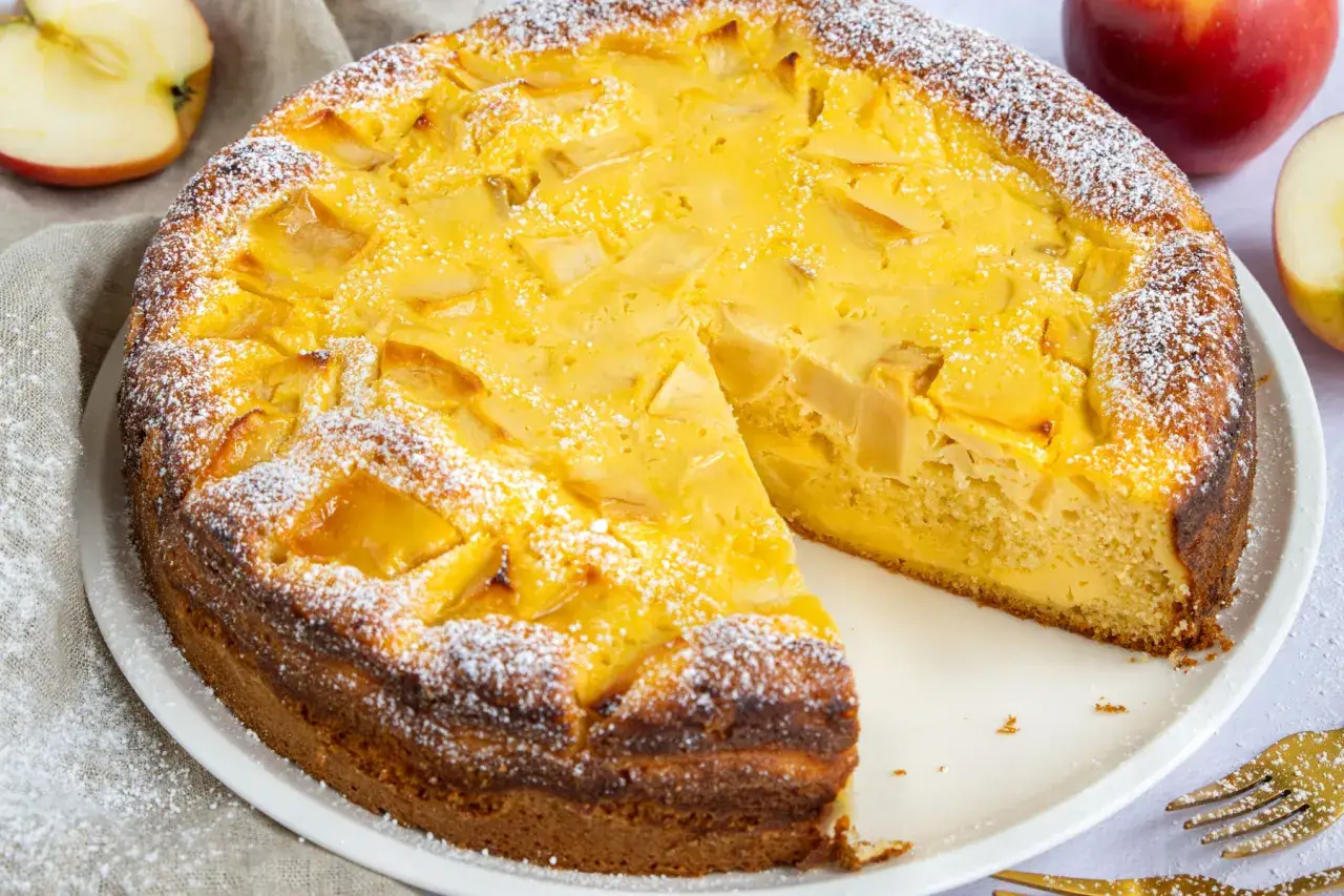 Ein saftiger Apfelkuchen mit Quark, bestäubt mit Puderzucker. Ein Stück fehlt bereits, bereit zum Genuss.