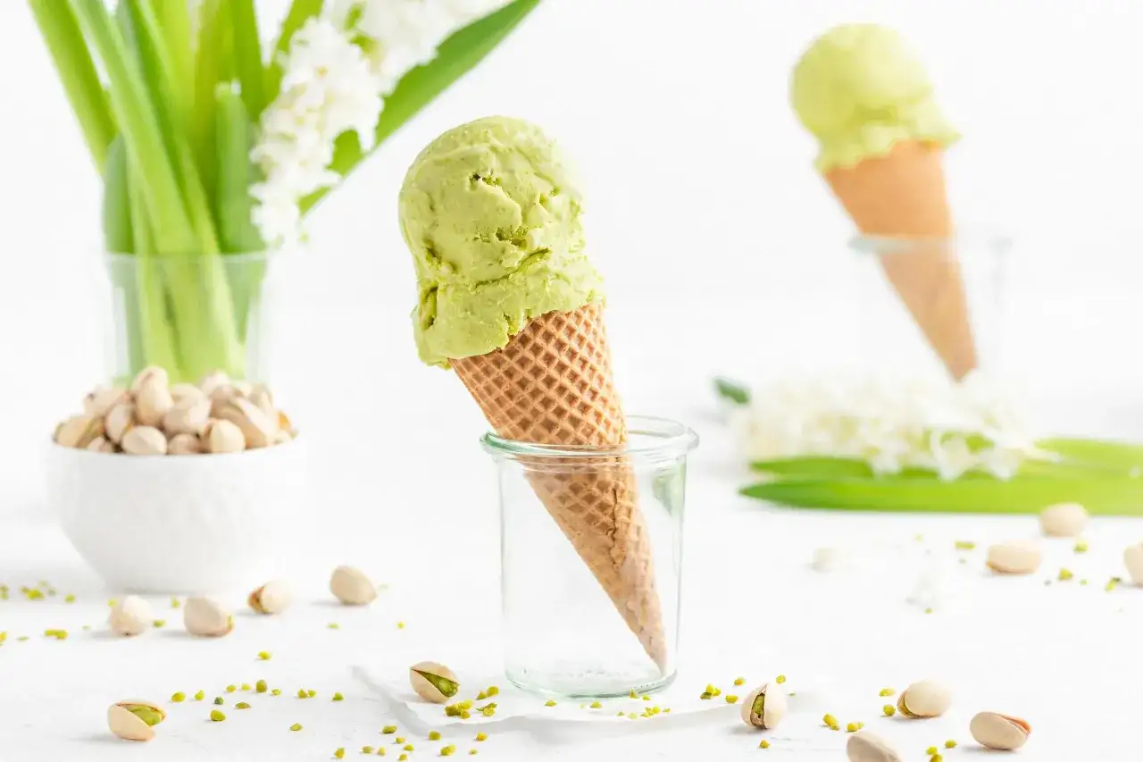 Ein cremiges Pistazieneis-Rezept, das Lust auf Sommer macht. Serviert in Waffeln, mit frischen Pistazien und Blumen.