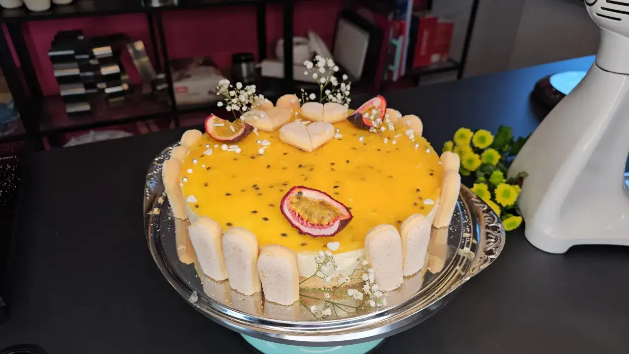 Eine köstliche Maracuja Torte mit Löffelbiskuits, Maracuja-Gelee und Herz-Keksen, verziert mit kleinen weißen Blüten und silbernen Perlen.