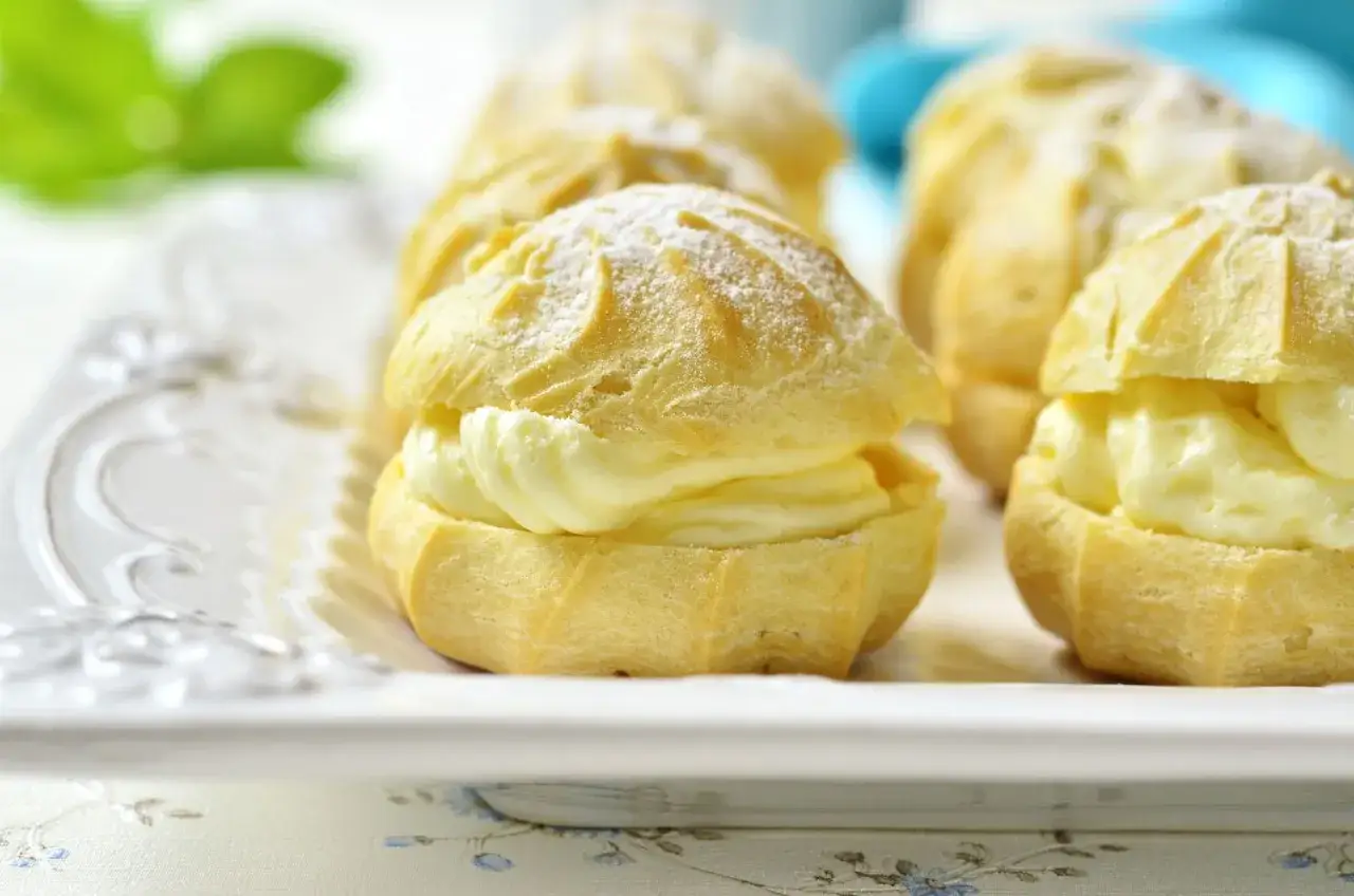 Saftige Windbeutel gefüllt mit cremiger Crema Pasticcera, bestäubt mit Puderzucker.
