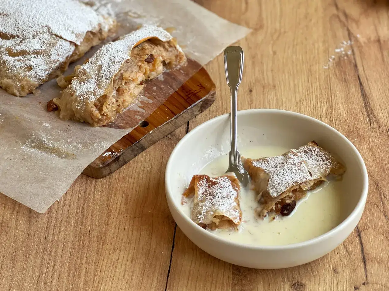 Ein köstliches Apfelstrudel Rezept, mit Puderzucker bestäubt und in Vanillesauce serviert.