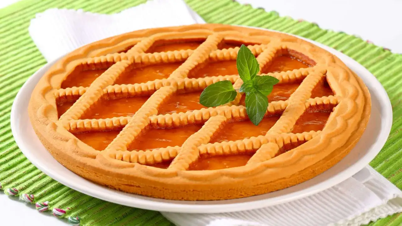 Eine köstliche Linzer Torte mit Gittermuster und Marmeladenfüllung, garniert mit einem Minzblatt.