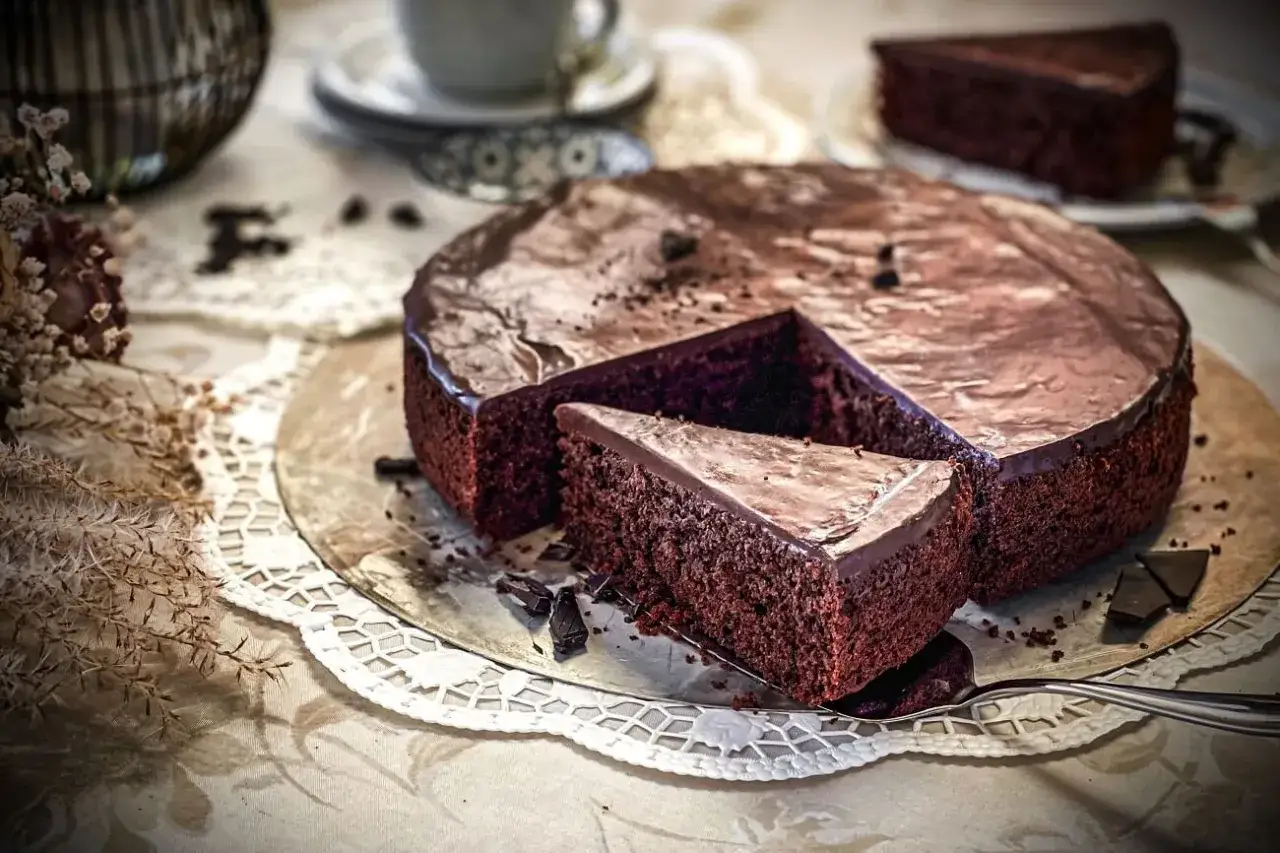 Ein saftiges Schokoladentorte Rezept, das mit glänzendem Schokoladenguss und einer abgetrennten Tortenscheibe verführt.