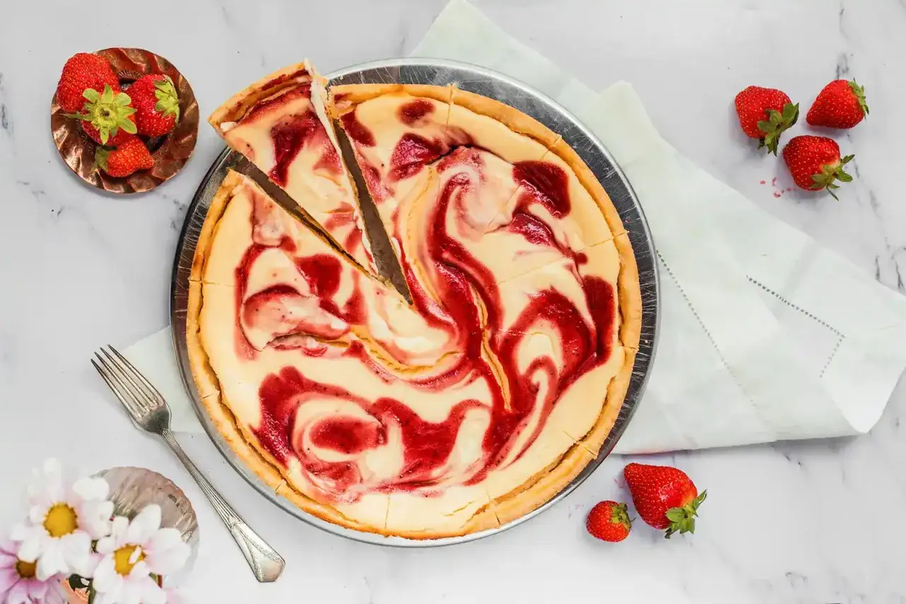 Ein köstlicher Strawberry Cheesecake mit wirbelnden Erdbeermarmeladenmustern, garniert mit frischen Erdbeeren und einer Gabel.