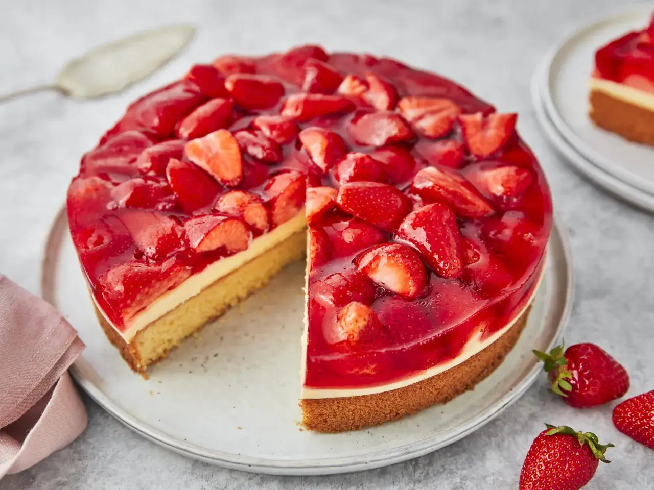 Ein saftiger Erdbeerkuchen mit Vanillepudding, bedeckt mit gl&auml;nzender Erdbeerglasur und frischen Erdbeerst&uuml;cken.