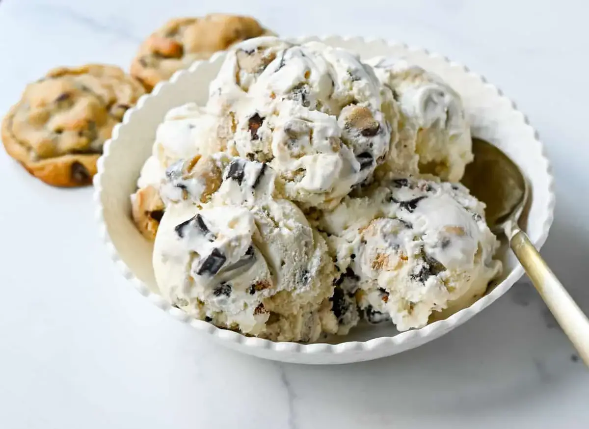Cremiges Cookie Dough Eis mit Schokoladenstückchen in einer Schüssel, daneben zwei Kekse.