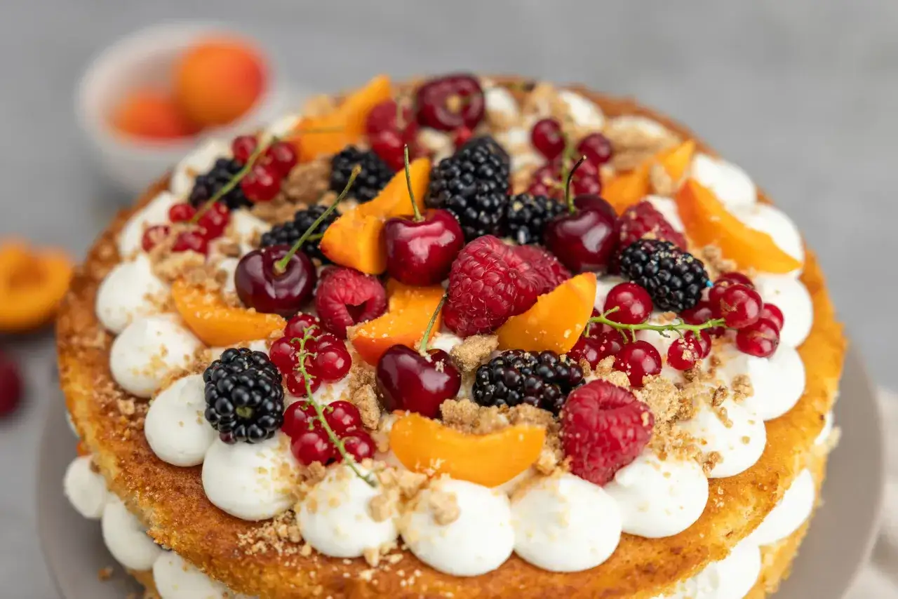 Ein fruchtiger Geburtstagskuchen mit Sahnetupfern, Kirschen, Beeren und Aprikosen. Ein tolles Rezept für jeden Anlass!