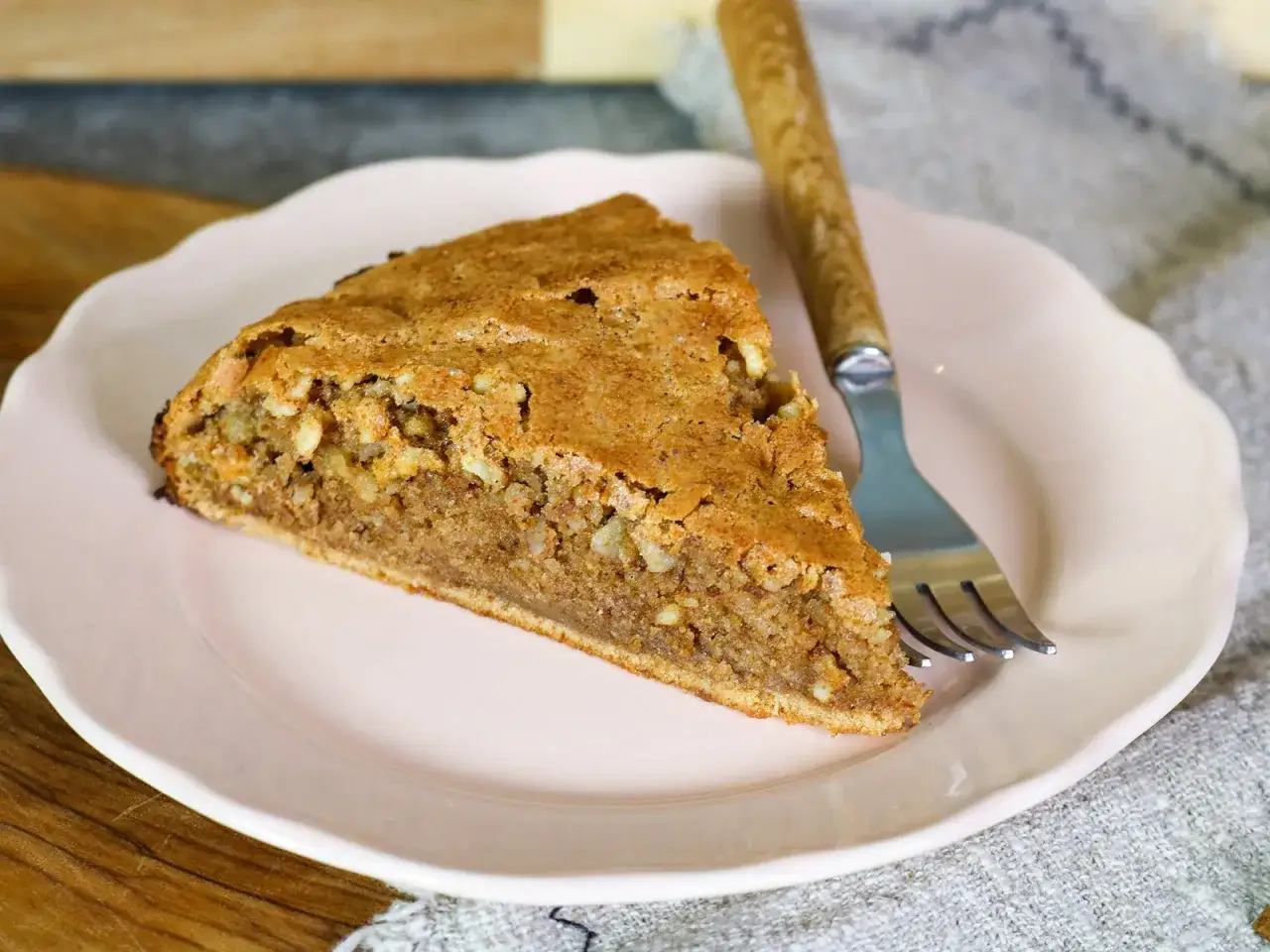 Ein Stück mallorquinischer Mandelkuchen mit Nüssen auf einem rosa Teller, bereit zum Genießen.