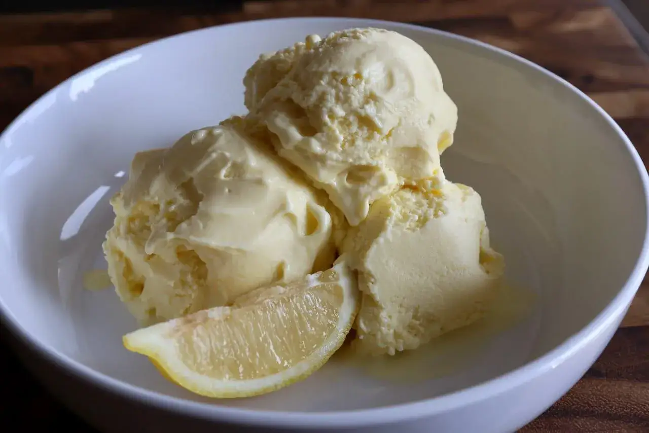 Cremiges Limoncello Eis in einer weißen Schale, garniert mit einer Zitronenspalte. Perfekt für heiße Tage!