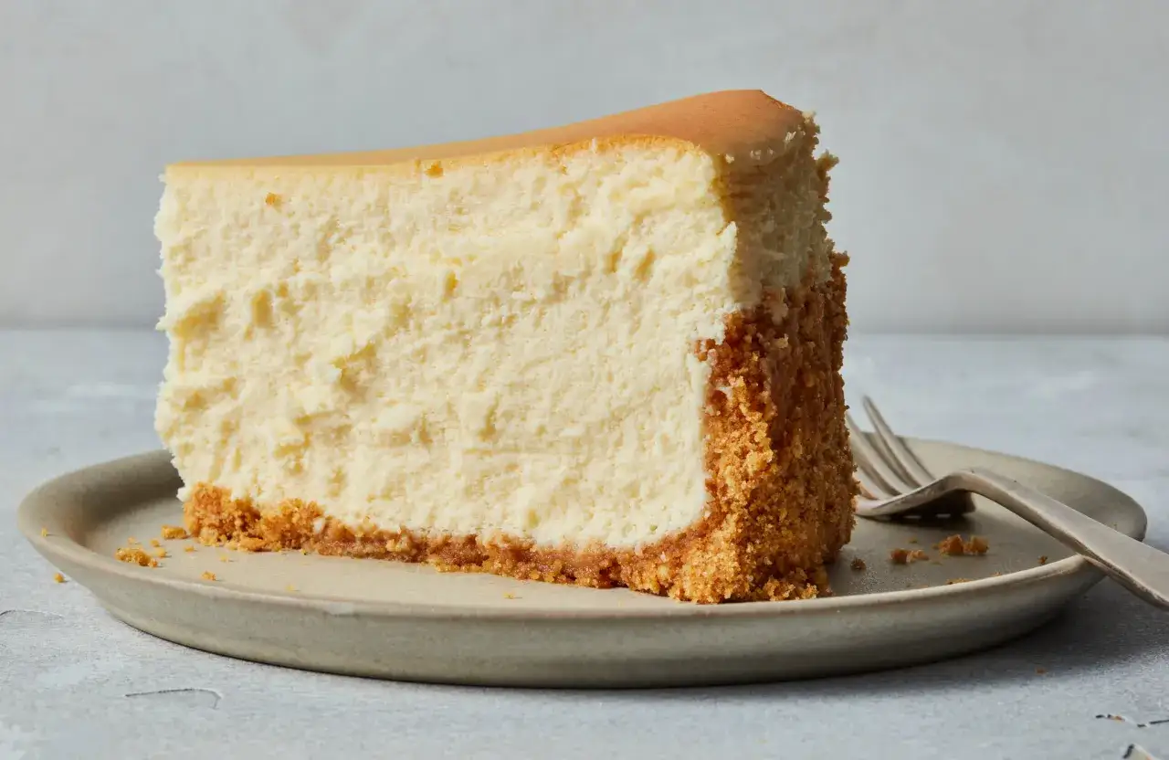 Ein Stück New York Cheesecake mit knusprigem Boden auf einem Teller, bereit zum Genießen.