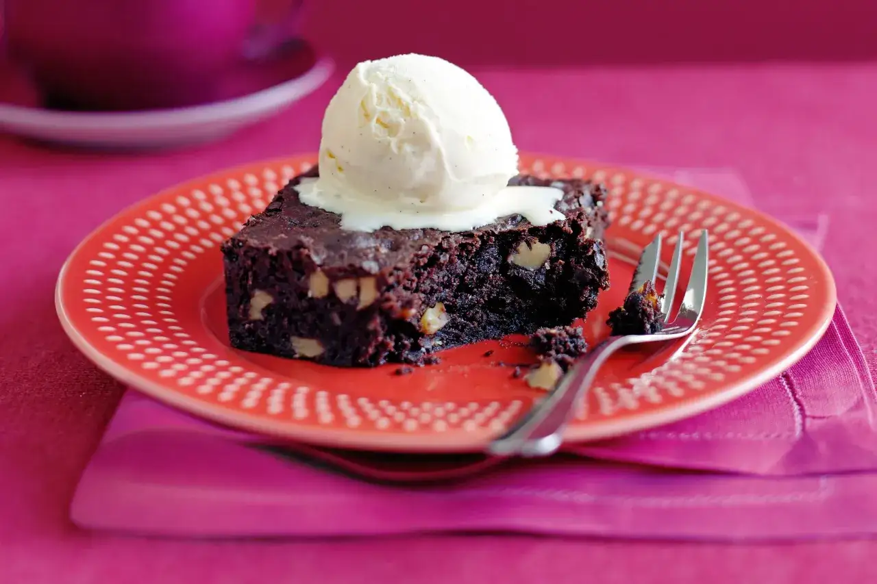 Ein Stück Schokoladenkuchen mit Walnüssen und einer Kugel Vanilleeis, perfekt für ein Brownie Rezept.