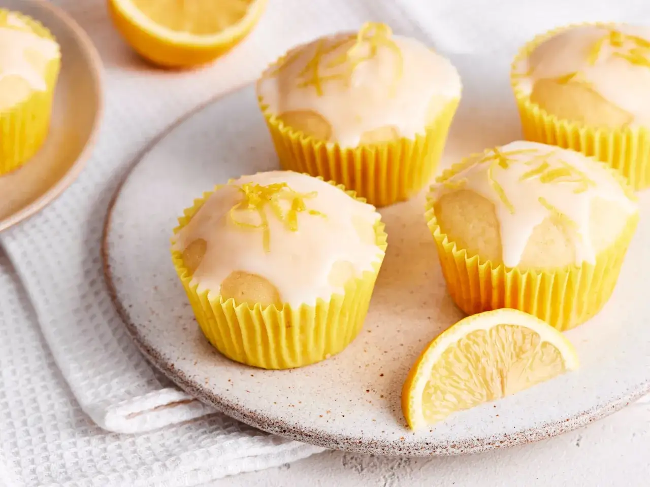 Saftige Buttermilch Muffins mit Zitronenglasur und Zesten. Ein Genuss für jeden Kaffeetisch.