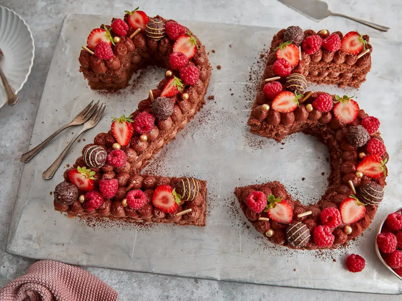 Eine köstliche Zahlentorte mit Biskuitboden, dekoriert mit Schokolade, Erdbeeren und Himbeeren, feiert den 25. Geburtstag.