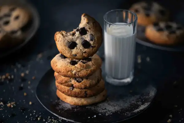 Ein Stapel saftiger American Cookies mit Schokoladenstückchen, daneben ein Glas Milch. Perfekt für das American Cookies Rezept.