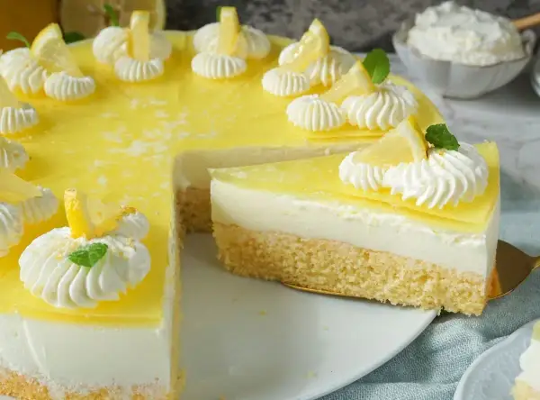 Eine köstliche zitronen torte mit Biskuitboden, cremiger Füllung und gelber Zitronenglasur, verziert mit Sahnetuffs und Zitronenspalten.