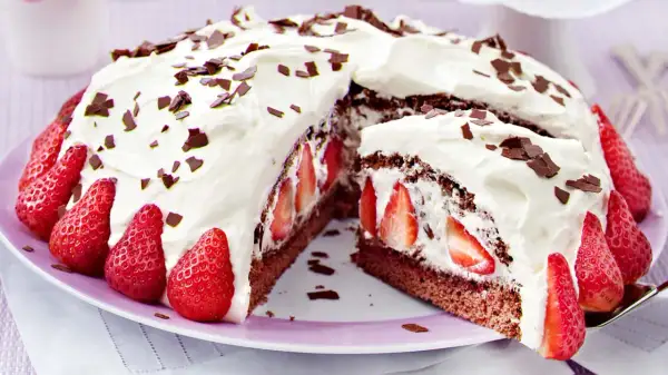Saftige Stracciatella Torte mit frischen Erdbeeren und Schokostückchen, üppig mit Sahne verziert.