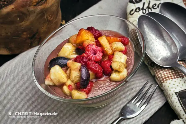 Schüssel mit cremigem Dessert und frischem Obstsalat aus Himbeeren, Bananen und Aprikosen. Perfekt für ein leichtes obstsalat rezept.