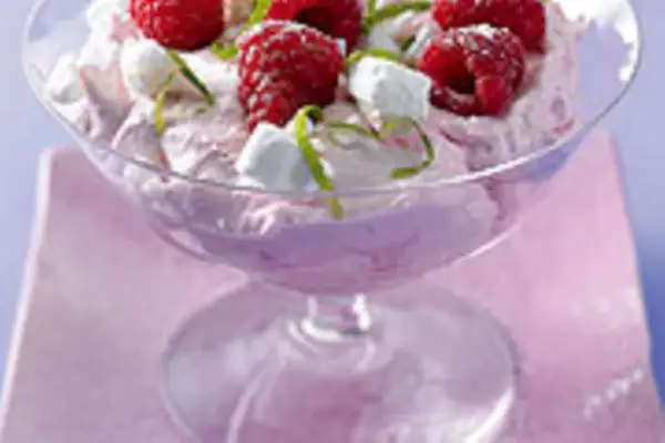 Himbeer-Mascarpone-Creme in einem Glas, garniert mit frischen Himbeeren, kleinen weißen Baiserstückchen und Zitronenmelisse.
