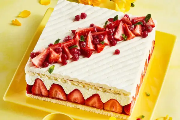 Rechteckiger Kuchen mit Erdbeeren und roter Johannisbeere auf leichter Erdbeer-Buttercreme, verziert mit Minze.